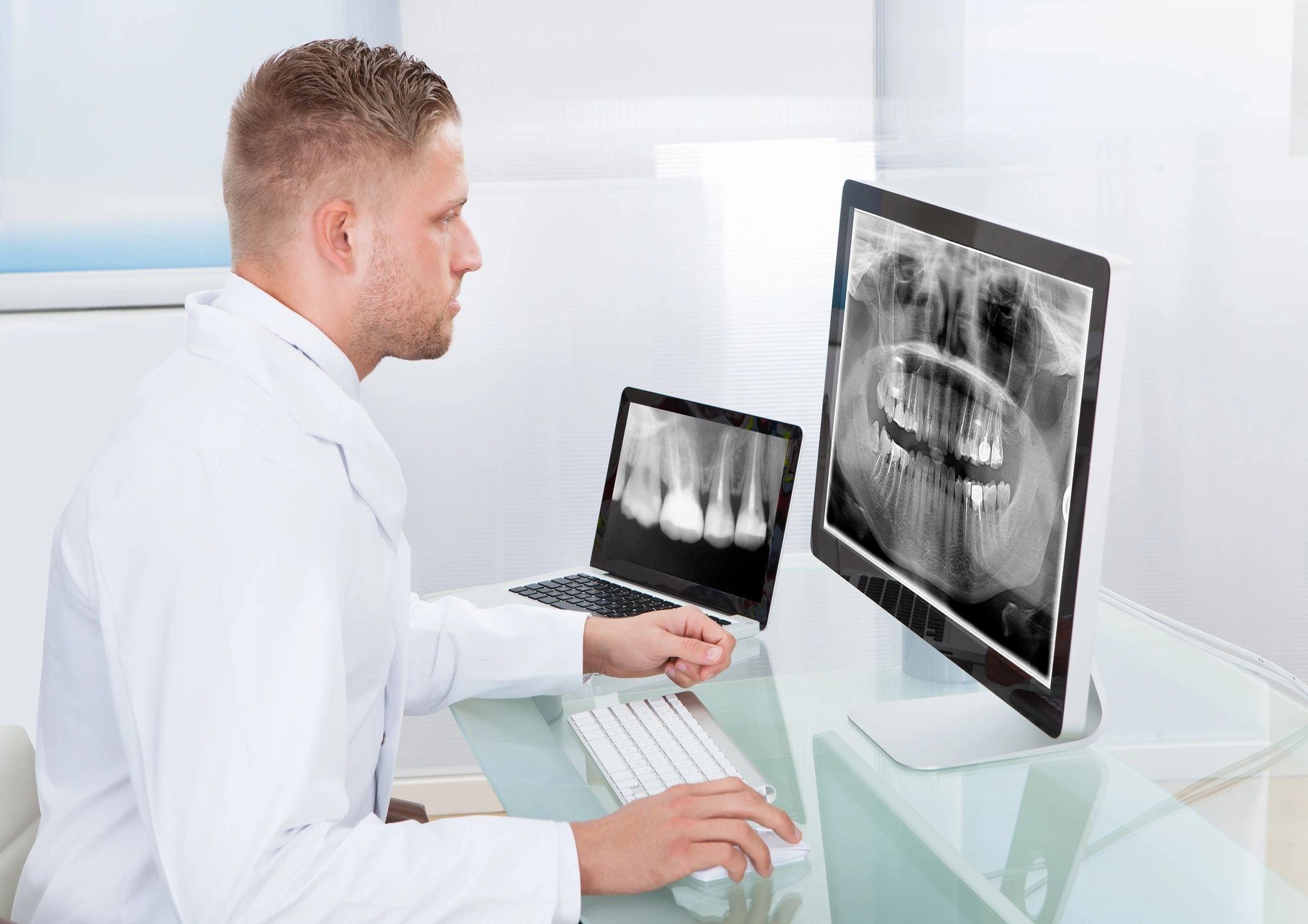 A man in white lab coat looking at computer screen.